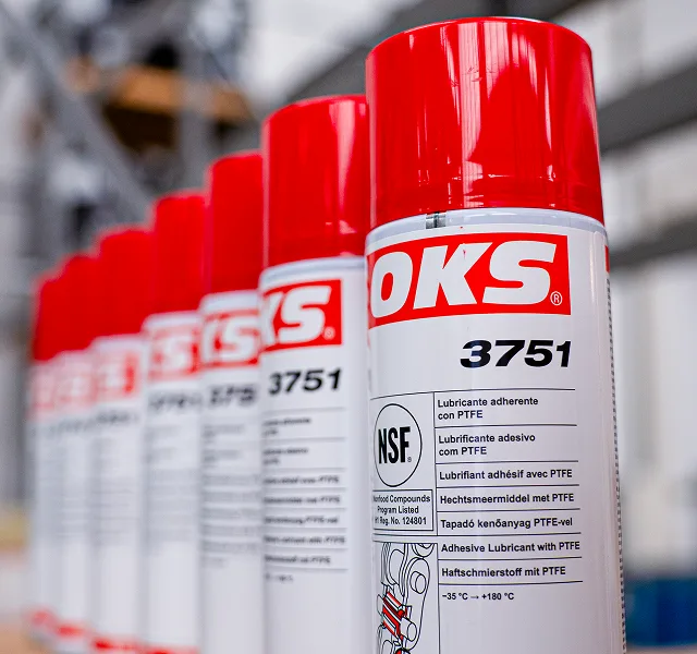 Latas spray de lubrificante adesivo OKS 3751 com PTFE alinhadas em ambiente industrial