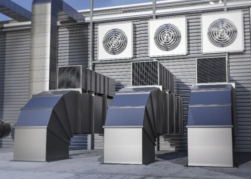 Condensadores e dutos de sistema HVAC industrial instalados na area externa de uma fabrica.