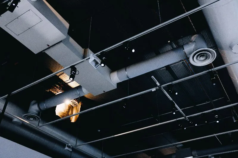 Dutos e tubulacoes de sistema de ventilacao HVAC instalados no teto de ambiente industrial